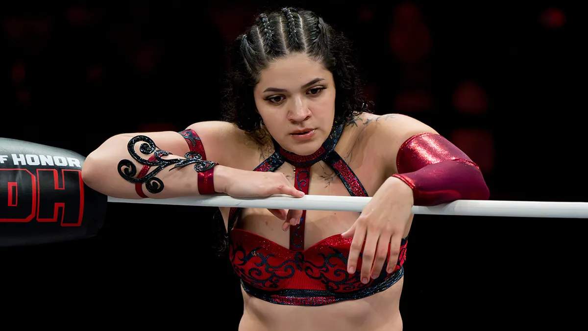Persephone posing on the ring ropes during a wrestling event.